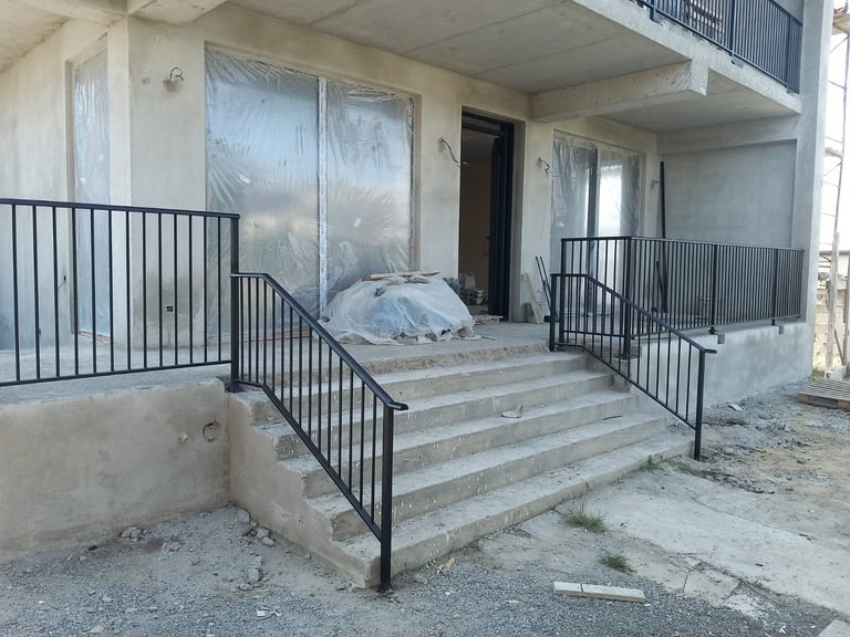 Abandoned building entrance with concrete steps, black metal railings, and plastic-covered doors and windows