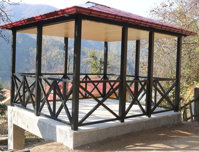 Modern open-sided gazebo with black frame, cream roof, and X-pattern railings on concrete base overlooking mountains