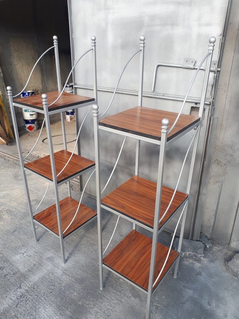 Two metal shelving units with wooden shelves and curved top frames, displayed in an industrial space